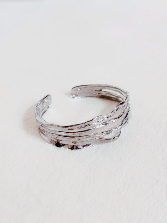 Accesorio tipo pulsera. Diseño asimétrico, plateado.
